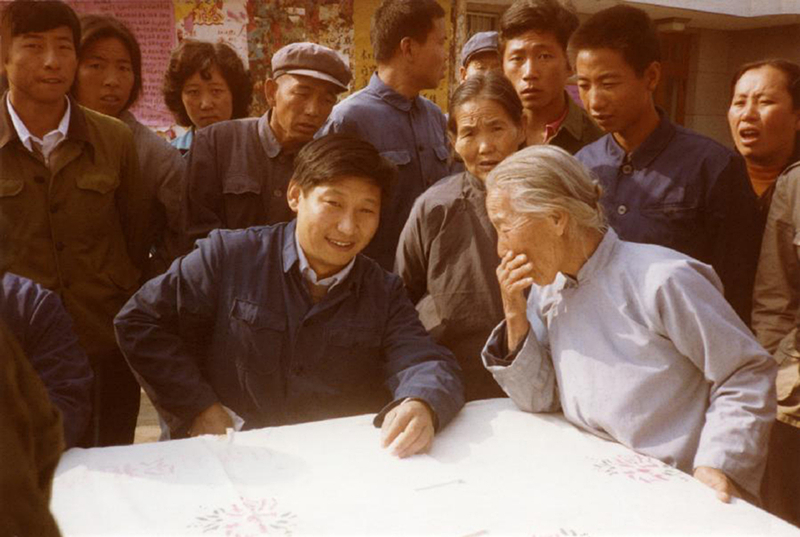 1983年，時(shí)任河北正定縣委書記的習(xí)近平（前排居中），臨時(shí)在大街上擺桌子聽取老百姓意見。